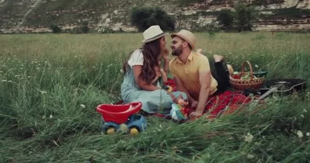 schöne junge Familie haben eine schöne Picknick-Zeit, legen sich auf die Decke in der Mitte des Berges, küssen und lächeln. 4k - Filmmaterial, Video