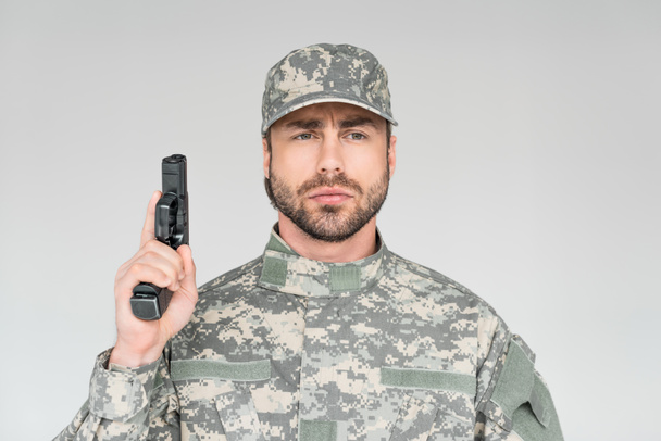 portrait of male soldier in military uniform holding gun isolated on grey - Photo, Image