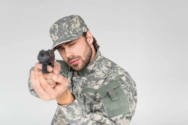 selective focus of male soldier in military uniform holding gun isolated on grey - Photo, Image