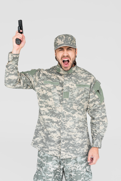 screaming male soldier in military uniform holding gun isolated on grey - Фото, изображение