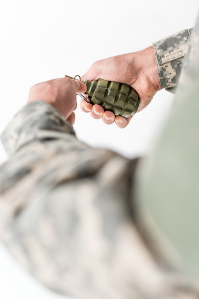 cropped shot of soldier holding grenade in hands on light backdrop - Foto, Bild