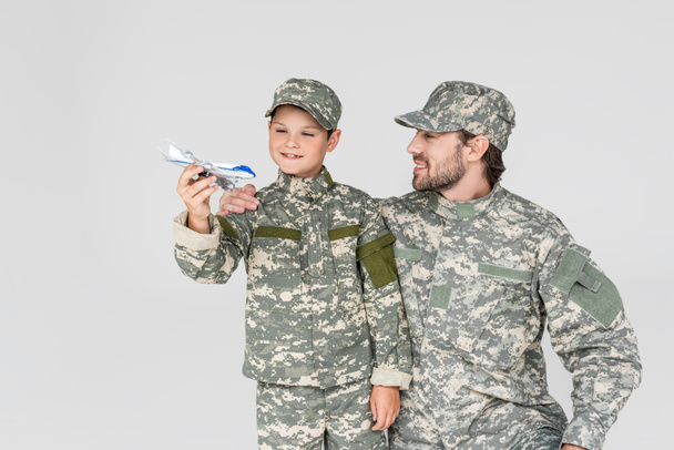 portret ojca i syna w wojskowych mundurach z samolotu zabawka na szarym tle - Zdjęcie, obraz
