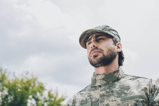 retrato de soldado confiado en uniforme militar con cielo nublado sobre fondo
 - Foto, imagen