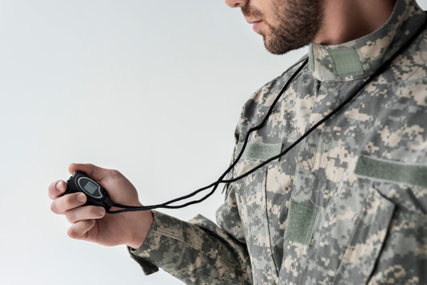 gedeeltelijke weergave van soldaat in militair uniform met stopwatch geïsoleerd op grijs - Foto, afbeelding