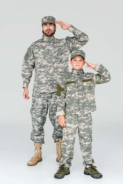 familia en uniformes militares saludando y mirando a la cámara sobre fondo gris
 - Foto, imagen