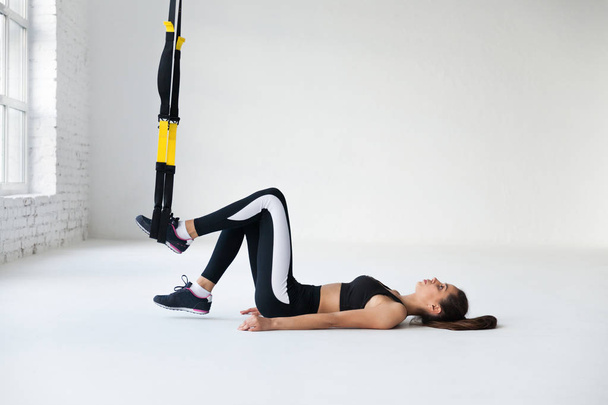 young woman doing yoga stretching exercises with trx fitness straps - Photo, Image