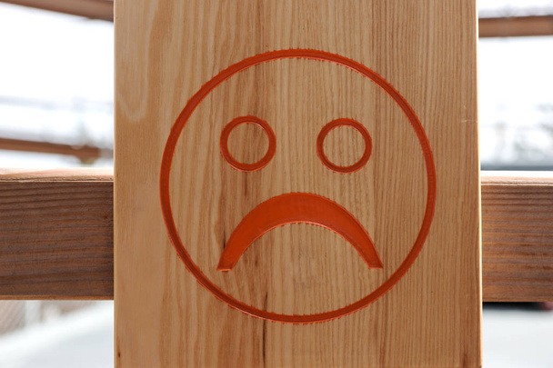 Rode ongelukkig smiley op bruin houten achtergrond - Foto, afbeelding