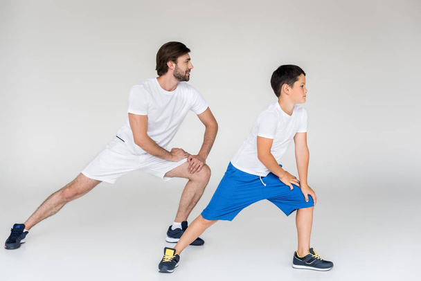 father and son in white shirts stretching on grey backdrop - Fotografie, Obrázek