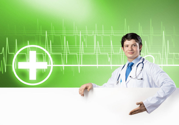 Young handsome doctor holding white blank banner. Place your text - Photo, image