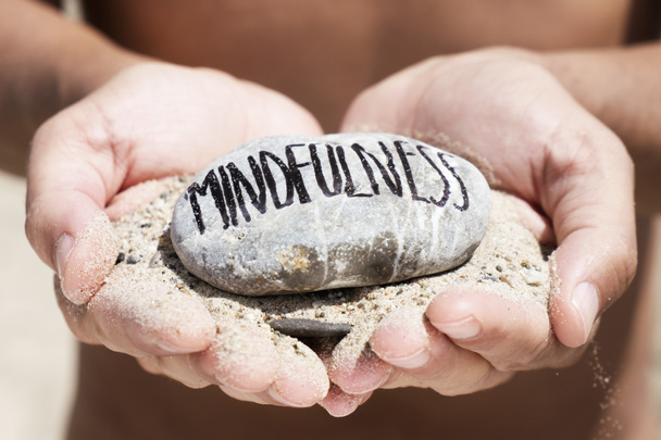 Vértes egy kaukázusi fiatalember, a tengerparton, egy maroknyi a kezében, és egy kő, a tetején a szöveg mindfulness írt ez a homok - Fotó, kép