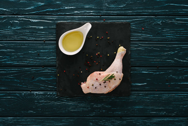 top view of chicken leg with pepper corns and oil on stone board - Zdjęcie, obraz