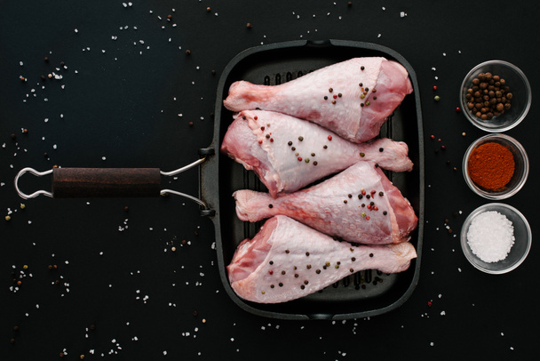 top view of turkey legs on grill pan with spices on black table  - Фото, зображення