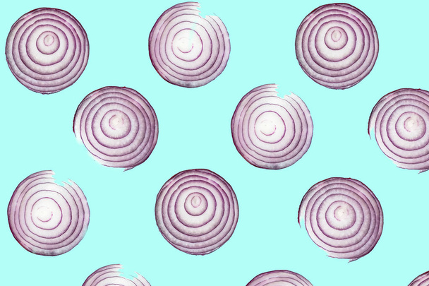 Top view pattern of fresh bright red onion rings on turquoise blue background. Shot from above of multiple sliced onions - Photo, image
