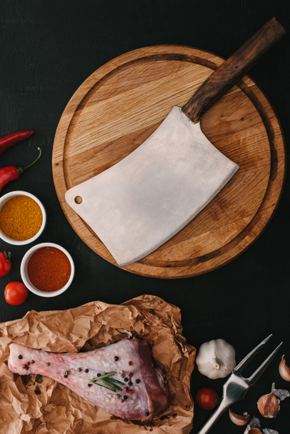 top view of raw turkey leg, spices and wooden cutting board with meat cleaver - Photo, Image