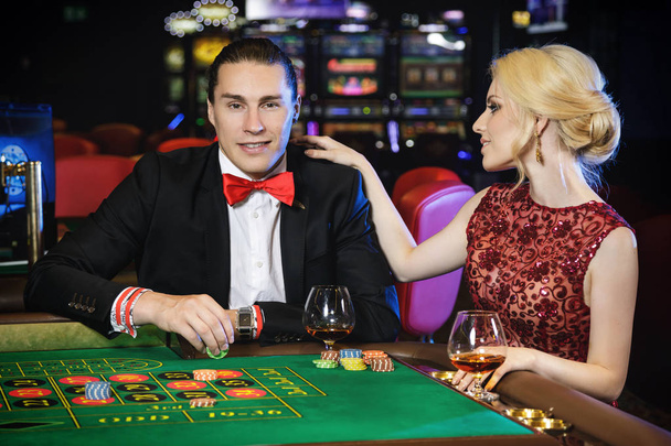Beautiful well dressed couple playing roulette in the casino - Фото, изображение