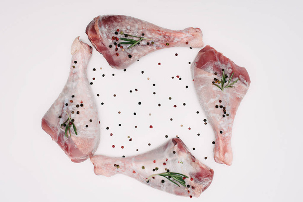 top view of raw turkey legs with pepper corns and rosemary, isolated on white - Φωτογραφία, εικόνα