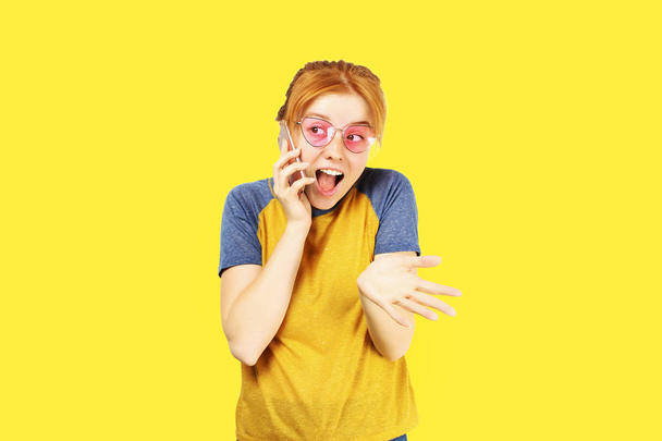 Porträt einer jungen irritierten Frau mit rosafarbener Katzensonnenbrille und Baseballhemd, die sich am Telefon streitet. Empörte schöne Frau spricht wütend und schreit auf Handy. Kopierraum Hintergrund, Nahaufnahme - Foto, Bild