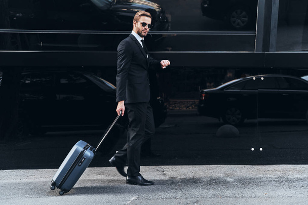 full length of businessman in suit walking in street with travel luggage  - 写真・画像