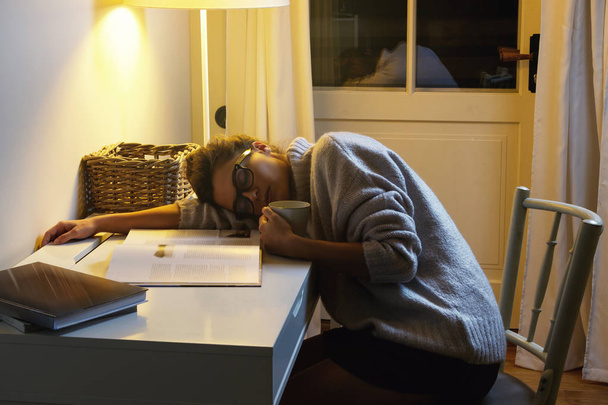 Väsynyt nainen opiskelija nukkuu pöydällä pitkän opiskelun ja lukemisen jälkeen kirjoja
 - Valokuva, kuva