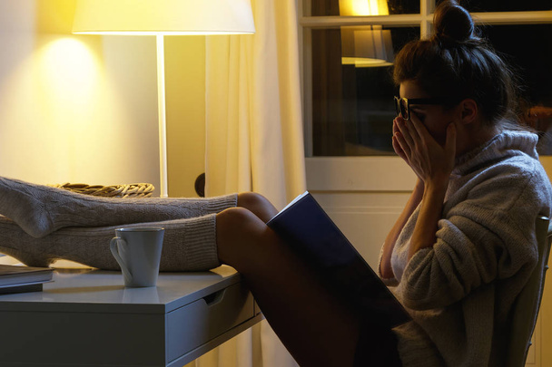 Tired student is rubbing her eyes after long reading at middle of the night - 写真・画像