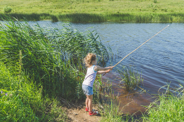girl, child on a summer day fishing with a fishing rod and a net - Valokuva, kuva