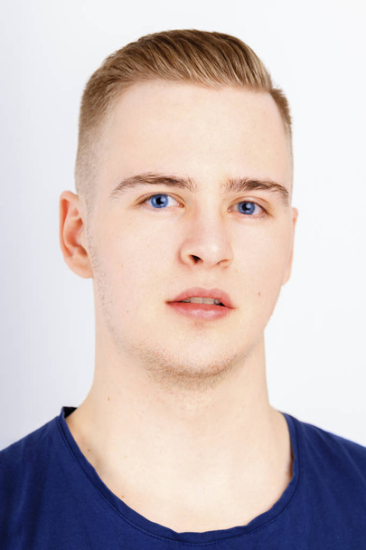 Young man in blue shirt poses in studio, close up portrait - 写真・画像