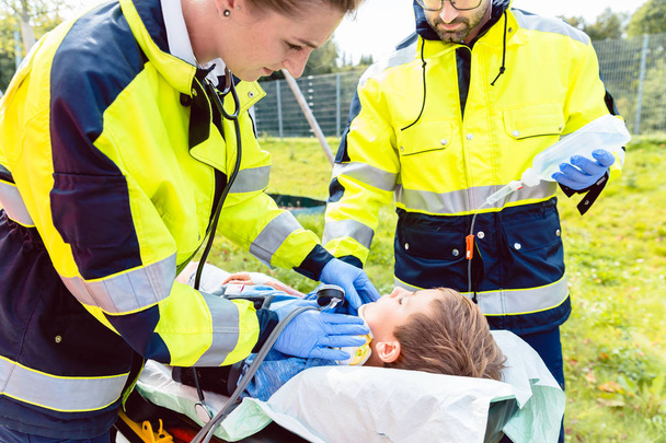 Paramédicaux mesurant la pression artérielle du garçon blessé
 - Photo, image