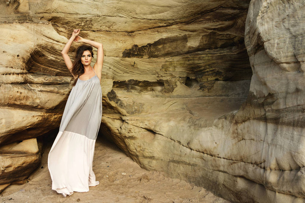 Young sensual woman in beautiful long dress beside the sand cliffs - Φωτογραφία, εικόνα