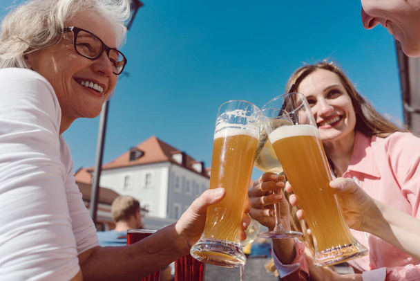 Trzy kobiety picie piwo pszeniczne na słoneczny dzień na zewnątrz - Zdjęcie, obraz