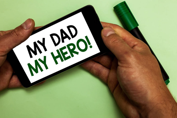 Writing note showing My Dad My Hero. Business photo showcasing Admiration for your father love feelings emotions compliment Human hand hold phone with texts touched green marker - Photo, Image