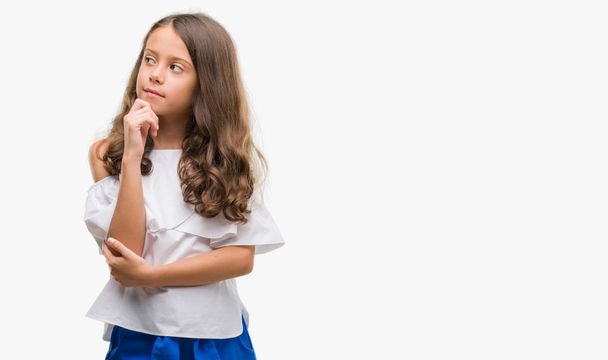 Brunette hispanic girl with hand on chin thinking about question, pensive expression. Smiling with thoughtful face. Doubt concept. - Foto, Imagem