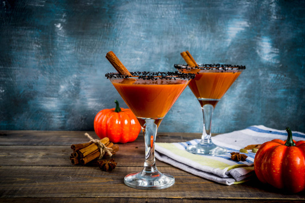Martini de calabaza picante de otoño con canela, estrellas de anís y decoración de sésamo negro, espacio de copia de fondo azul oscuro
 - Foto, imagen