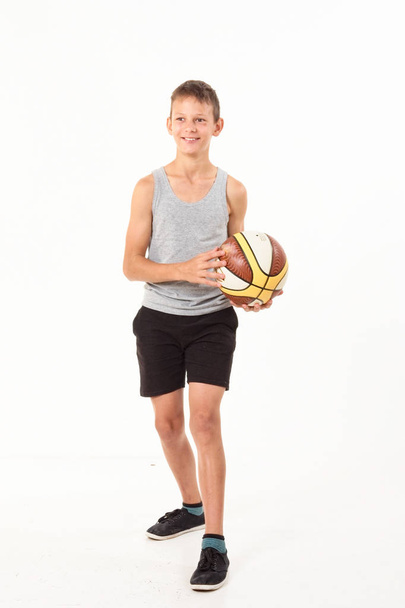 Έφηβος με μια μπάλα του μπάσκετ σε λευκό φόντο - Φωτογραφία, εικόνα