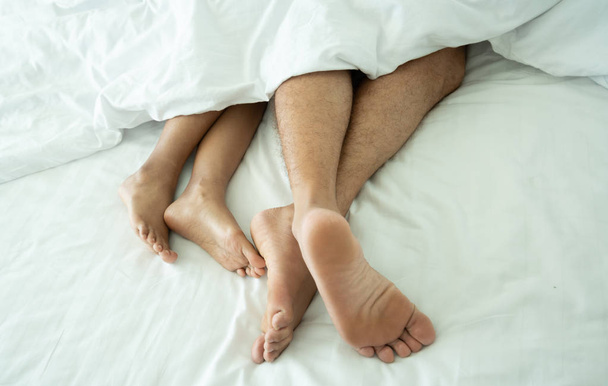 Close up of the feet of a couple on white bed and blanket - Fotografie, Obrázek