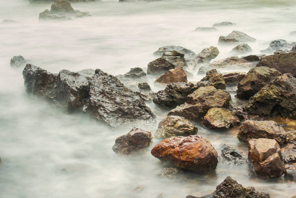 Lunga esposizione mare con onde schiumose spruzzi contro una riva rocciosa della Thailandia al mattino
 - Foto, immagini