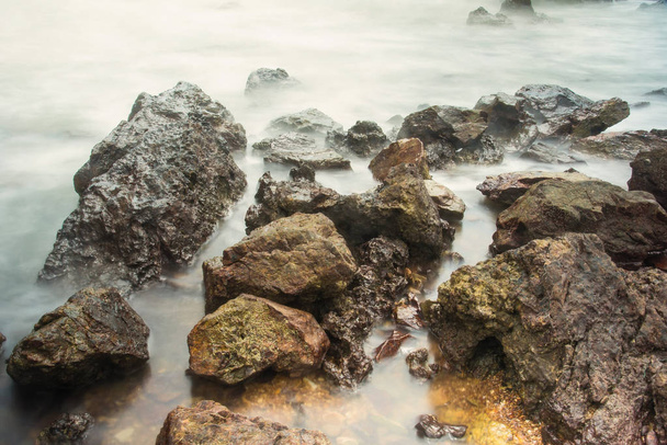 Hosszú expozíciós seascape habos hullámok fröccsen egy sziklás partján Thaiföld ellen a reggeli ideje - Fotó, kép