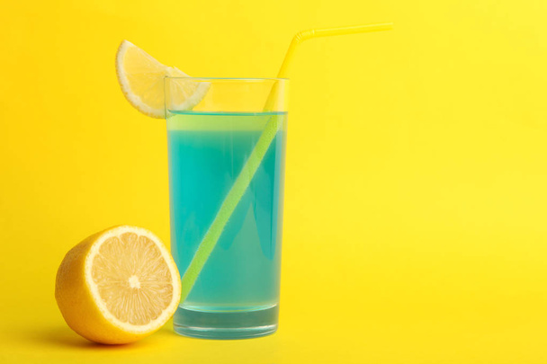Koktajl alkoholowy błękitne laguny z plasterkiem cytryny w szklance na żółtym tle. Miejsce. - Zdjęcie, obraz