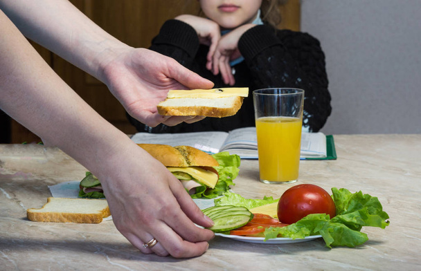 Mother prepares a sandwich for a child in school - Фото, изображение