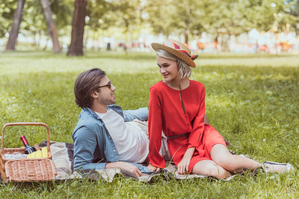 pareja sentada en una manta en el parque y mirándose
 - Foto, imagen