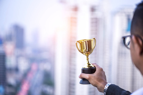Mão do presidente empresário segurando troféu de ouro, prêmio vencedor de negócios
 - Foto, Imagem