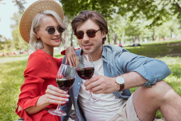 happy couple clinking with glasses of wine in park - Foto, imagen