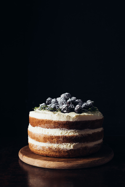 close-up shot of delicious blackberry cake on wooden cutting board and on black - 写真・画像