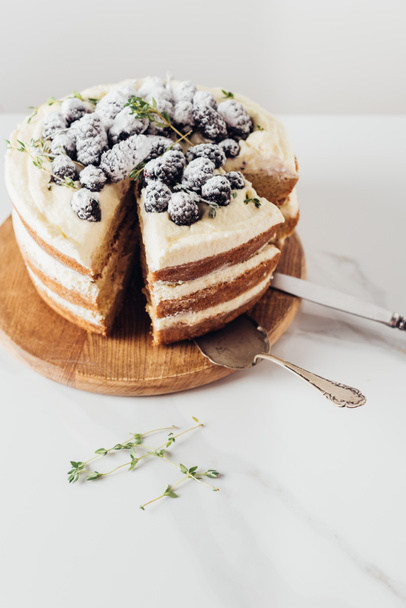 close-up shot of freshly baked sliced blackberry cake on wooden cutting board with cake server - Zdjęcie, obraz