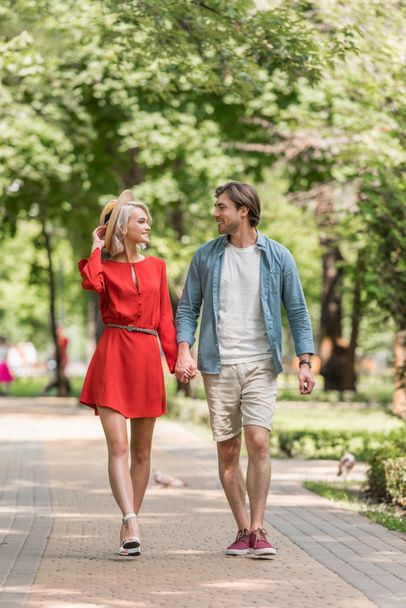 girlfriend and boyfriend holding hands and walking together in park - Photo, Image