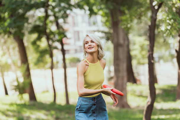 attractive blonde girl throwing frisbee disk in park  - Foto, Imagen