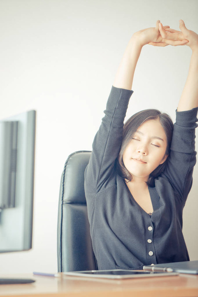 Happy business woman is relaxing and stretching out in office - Foto, immagini
