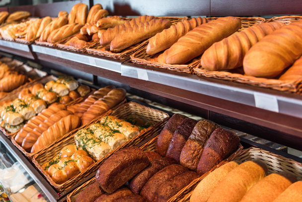 selective focus of freshly baked various bread in pastry department of grocery store - Photo, Image