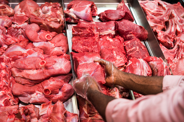 Μερική άποψη των αρσενικών χασάπη λαμβάνοντας ωμό κρέας σε σούπερ μάρκετ  - Φωτογραφία, εικόνα