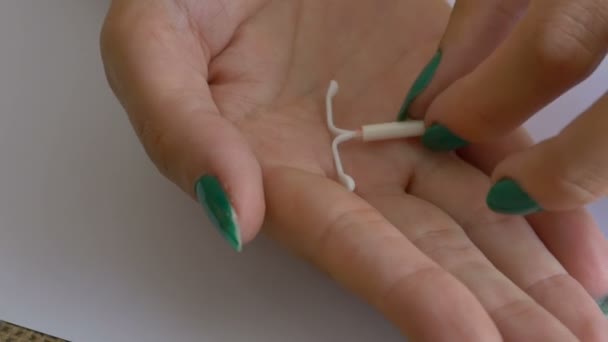 Woman showing a birth control device (IUD) in her palm. An intrauterine device (IUD), also known as intrauterine contraceptive device (IUCD or ICD) or coil, is a small, often T-shaped birth control device that is inserted into a woman's uterus to pre - Footage, Video