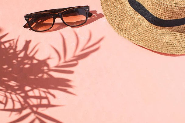 トラベル コンセプト夏シーズン冒険女性アクセサリー フラット置くサングラスわら帽子ピンク背景平面図コピー スペース熱帯の葉影美しい組成 - 写真・画像